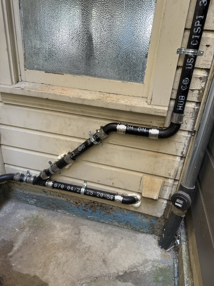 Exterior drain and vent piping with hub couplings installed along a Dallas home foundation